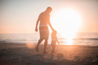 man holding girl heading towards sea by Derek Thomson courtesy of Unsplash.